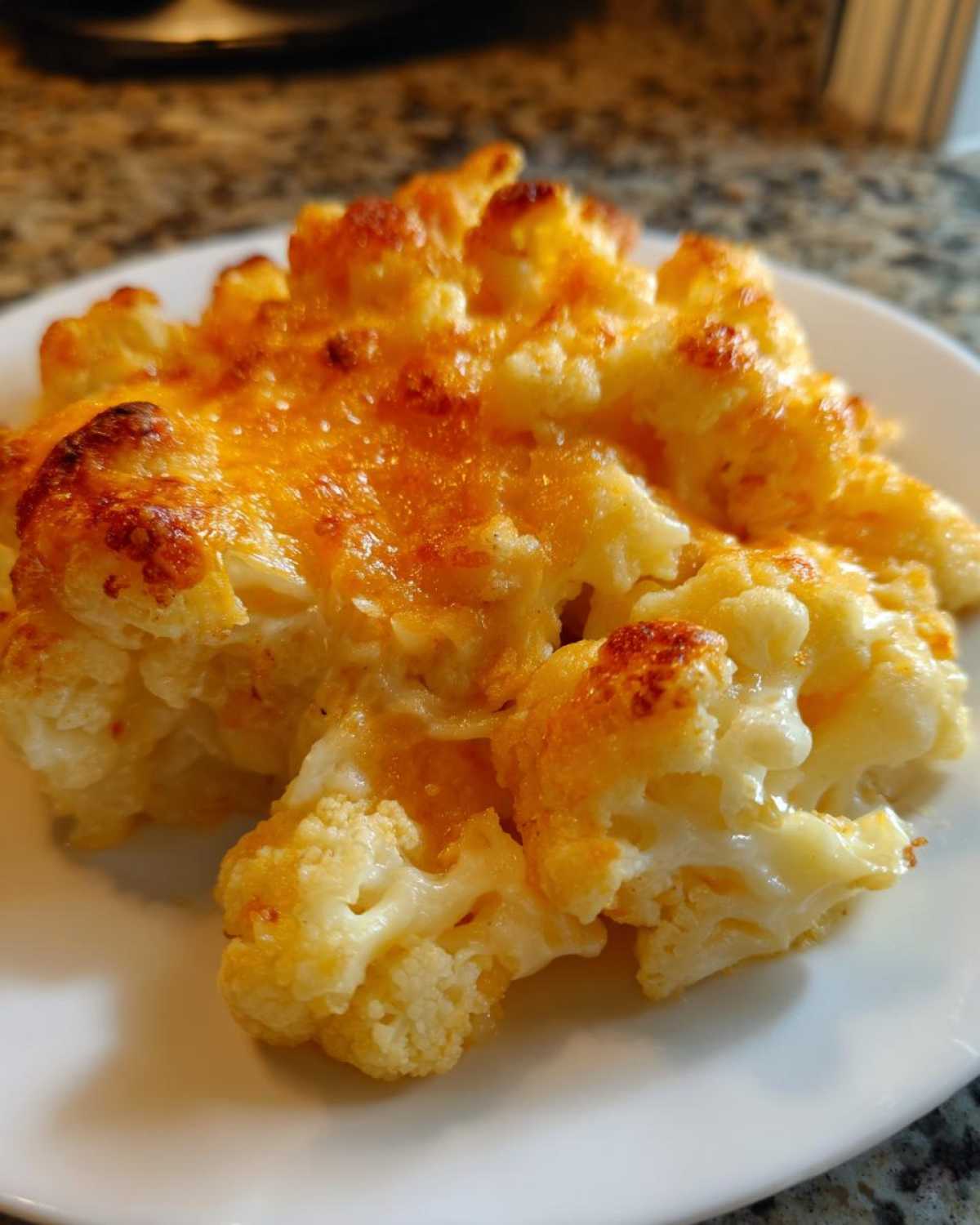 A close-up of a serving of Keto Cauliflower Mac and Cheese with a golden, bubbly cheese topping.
