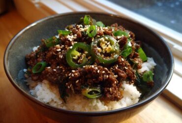 Close-up of Korean Ground Beef Bulgogi Bowls served over white rice, topped with jalapeños and sesame seeds.