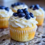 Close-up of a Lemon Blueberry Cupcakes with Cream Cheese Frosting topped with fresh blueberries.