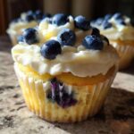 Close-up of a Lemon Blueberry Cupcake topped with cream cheese frosting and fresh blueberries.