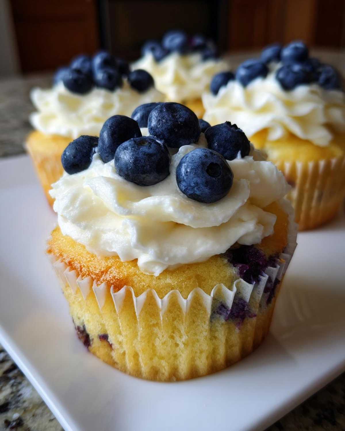 Close-up of a Lemon Blueberry Cupcake topped with swirled cream cheese frosting and fresh blueberries.