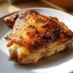 Close-up of a perfectly roasted Lemon Garlic Roasted Chicken Thighs with crispy, golden-brown, seasoned skin.