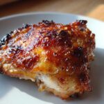 Close-up of a perfectly roasted Lemon Garlic Roasted Chicken Thighs with crispy, glazed skin.