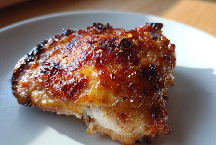 Close-up of a perfectly roasted Lemon Garlic Roasted Chicken Thighs with crispy, glazed skin.