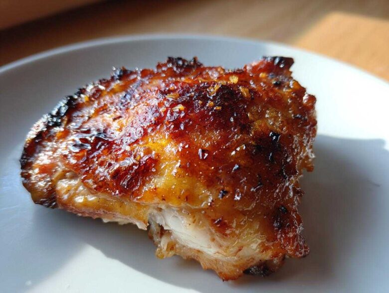Close-up of a perfectly roasted Lemon Garlic Roasted Chicken Thighs with crispy, glazed skin.