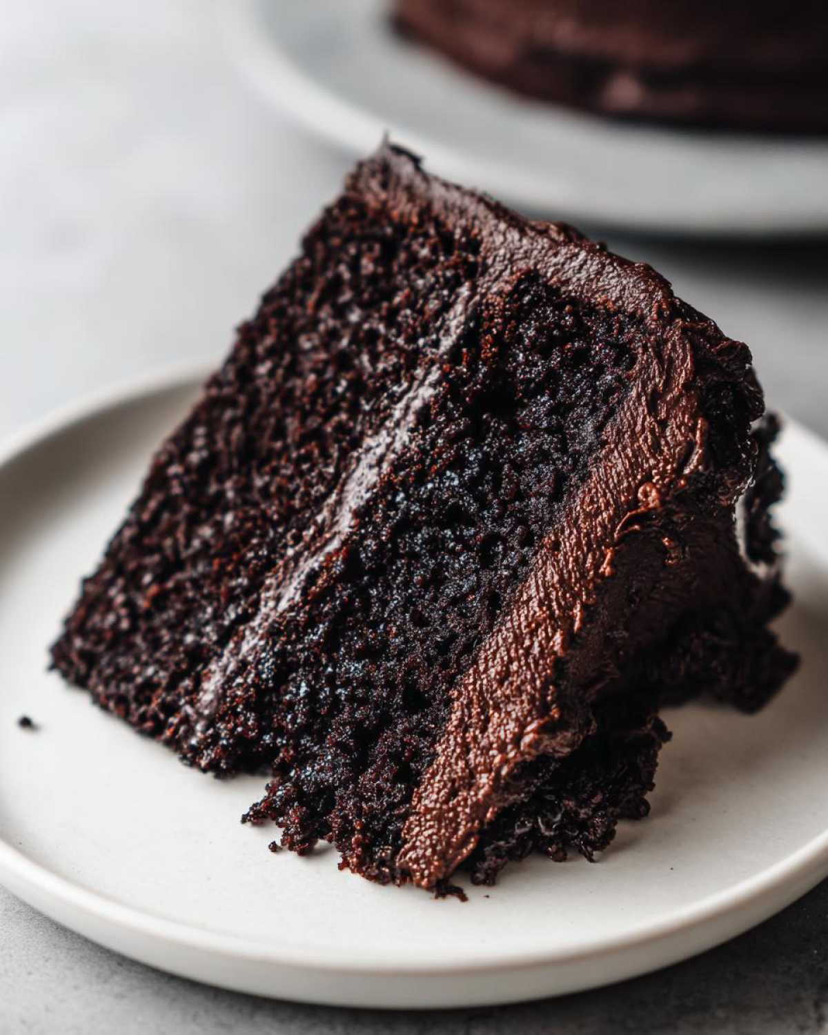Close-up of a rich, moist slice of Gluten-Free Chocolate Cake covered in thick chocolate frosting.