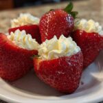 Close-up of several bright red No-Bake Cheesecake Stuffed Strawberries arranged on a white plate.