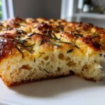 Close-up of a slice of No-Knead Skillet Focaccia showing its airy crumb and rosemary topping.