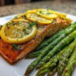 A perfectly cooked fillet of One-Pan Lemon Garlic Salmon with roasted asparagus spears, topped with lemon slices.