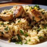 Close-up of tender chicken pieces served over creamy One-Pot Chicken and Rice with Lemon and Herbs, garnished with parsley.