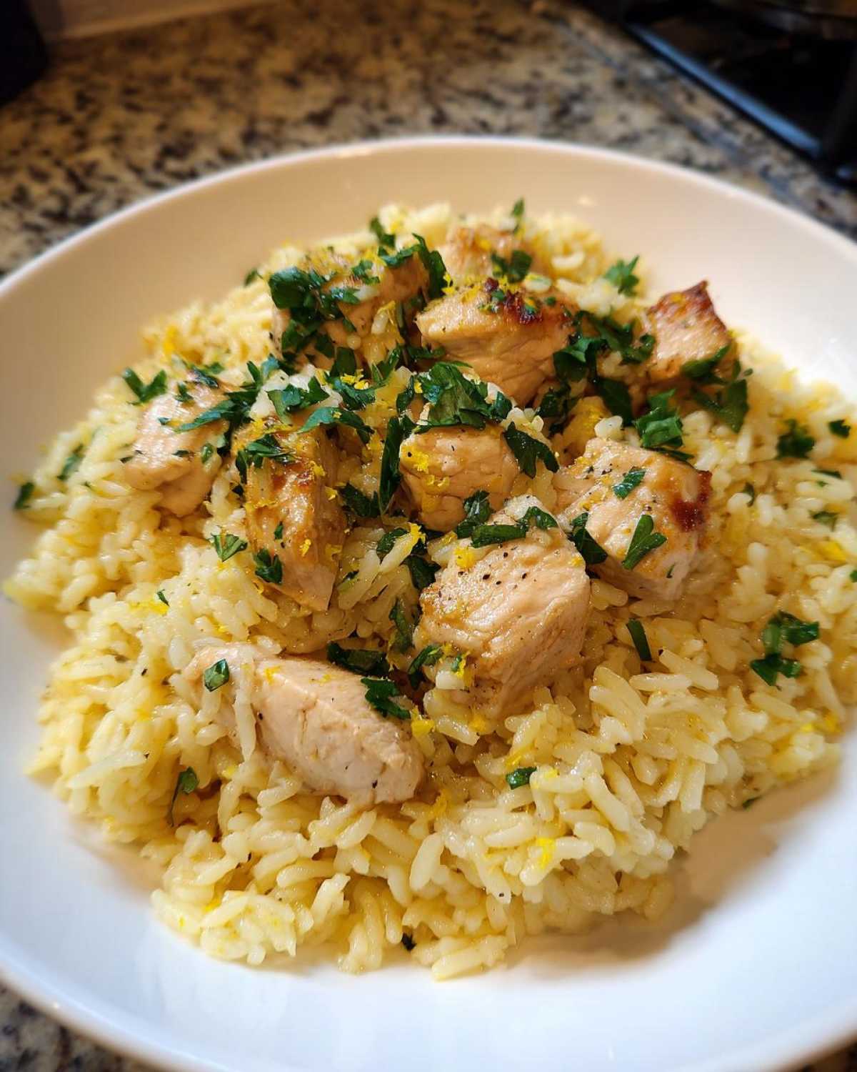 Close-up of One-Pot Chicken and Rice with Lemon and Herbs, topped with chicken pieces and fresh parsley.