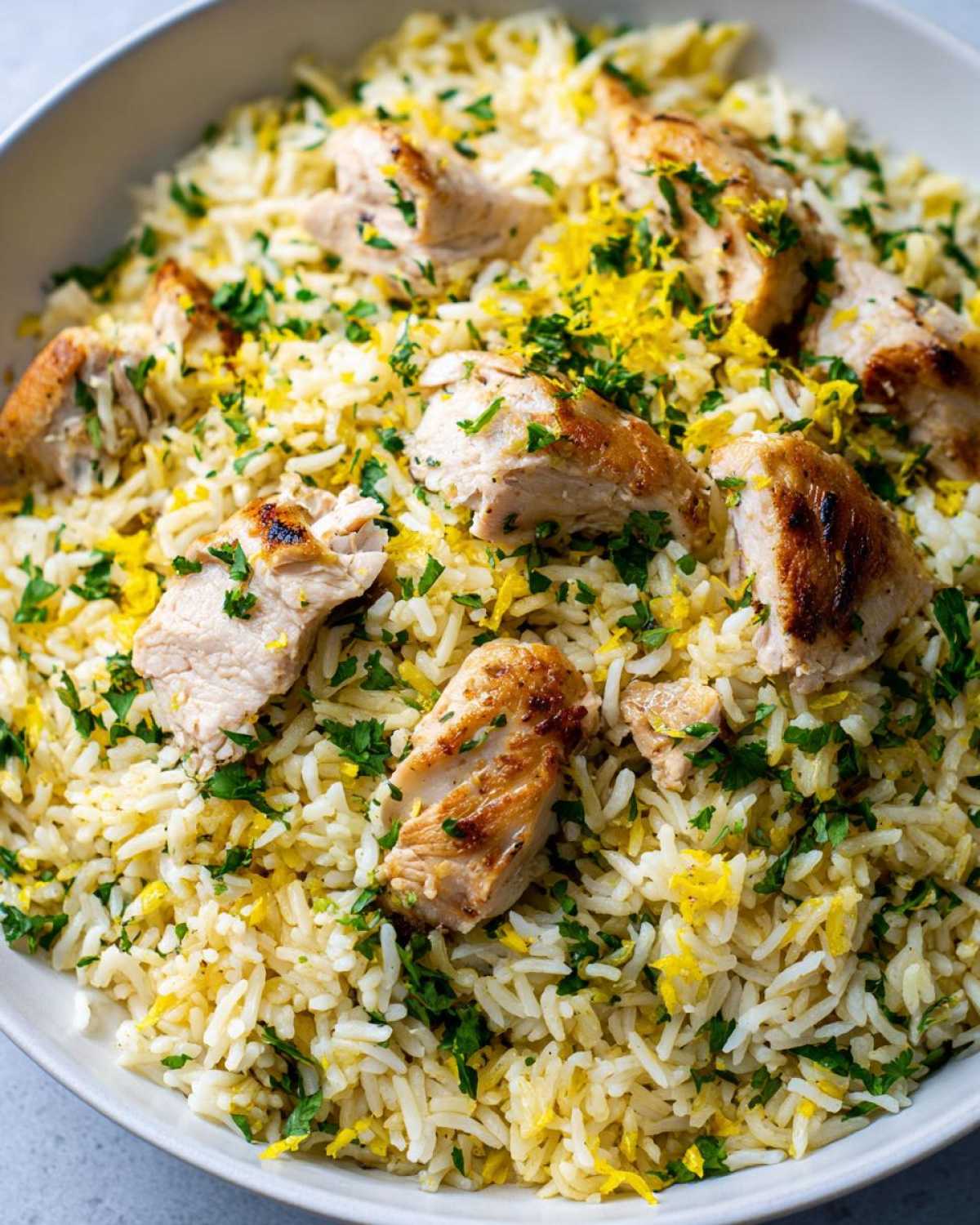 Close-up of One-Pot Chicken and Rice with Lemon and Herbs, topped with grilled chicken pieces and fresh parsley.