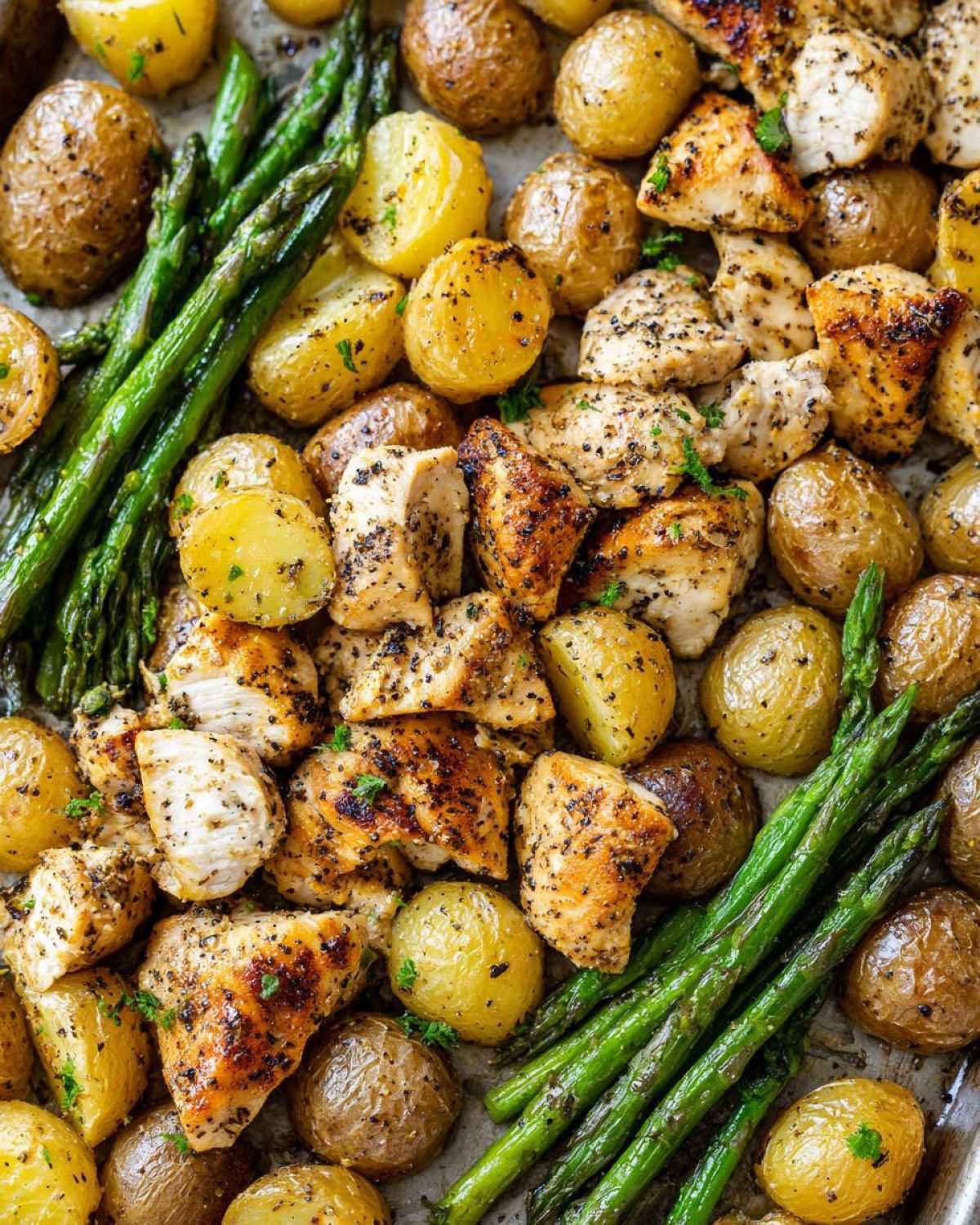 Close-up of Sheet Pan Lemon Pepper Chicken and Potatoes with roasted asparagus.