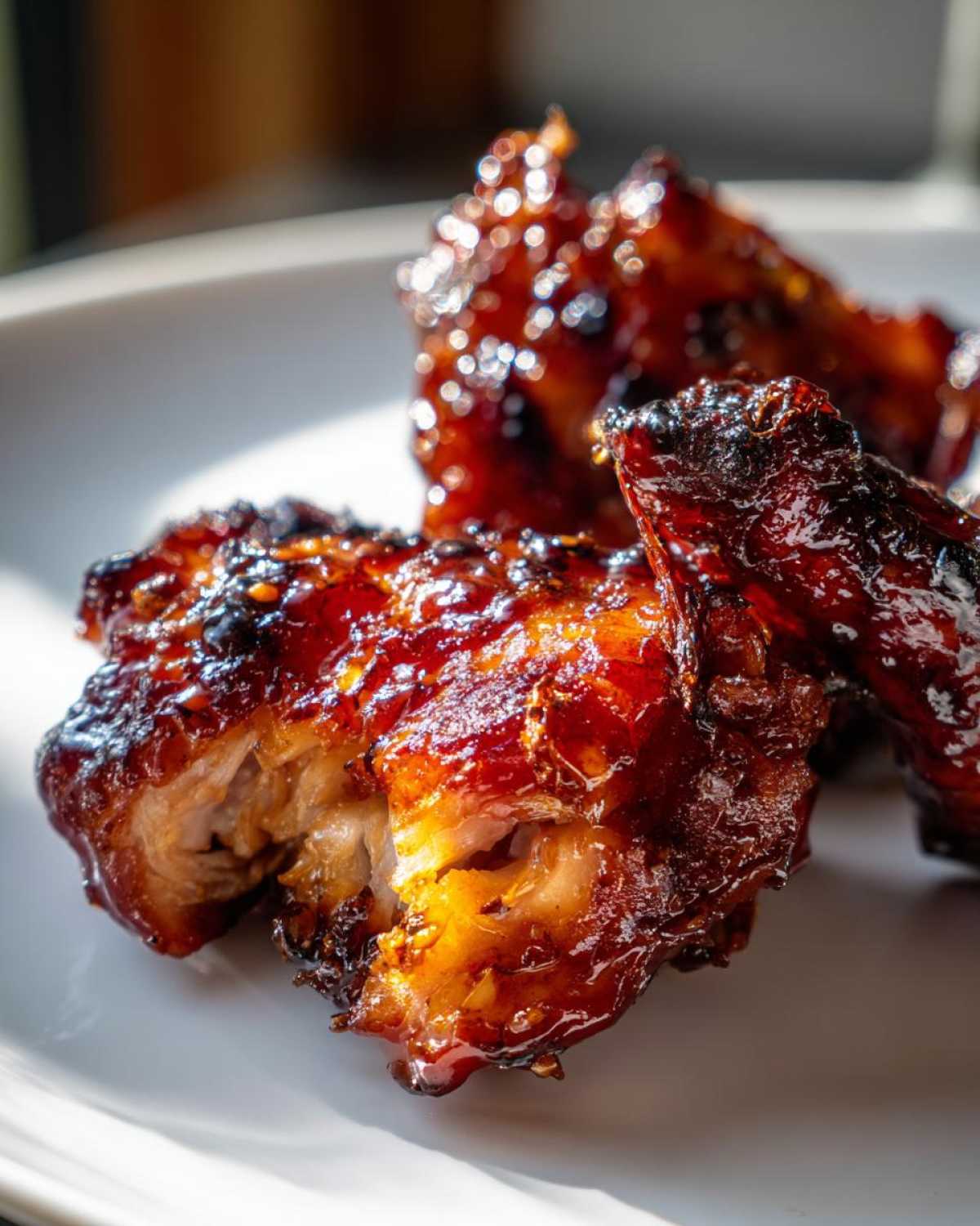 Close-up of glistening, caramelized Spicy Honey Garlic Air Fryer Chicken Thighs on a white plate.