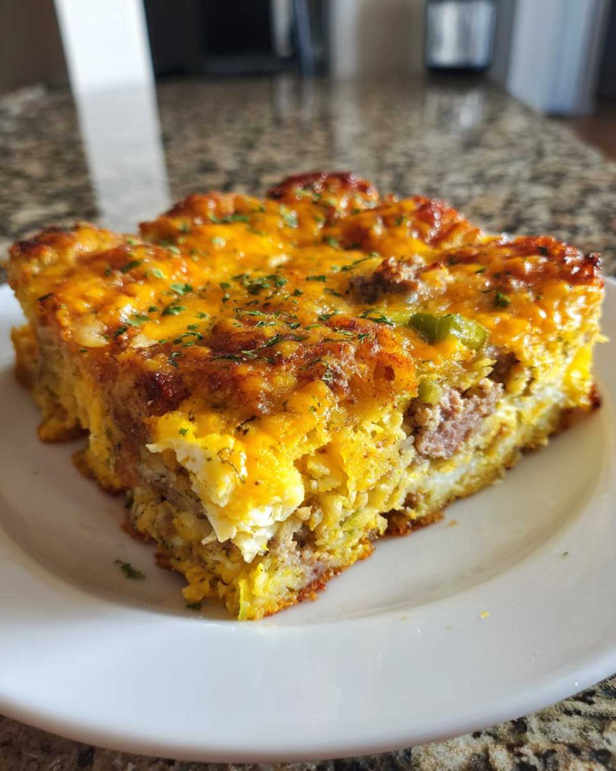 A hearty slice of Tater Tot Breakfast Casserole with sausage, eggs, and melted cheddar cheese.