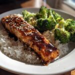 A piece of glazed Teriyaki Salmon served over white rice with roasted broccoli florets.