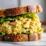 Close-up of a hearty Vegan Chickpea Salad Sandwich made with whole-grain bread, lettuce, and creamy chickpea filling.