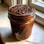 Close-up of thick Vegan Chocolate Chia Pudding filling a glass jar, showing the texture of the soaked chia seeds.