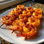 Close-up of perfectly cooked Air Fryer Crispy Cajun Shrimp Skewers arranged on a white plate.