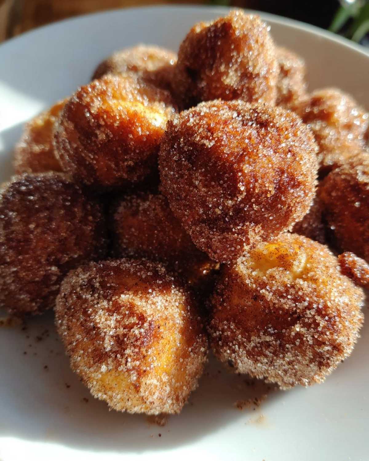 A close-up photo of several Air Fryer Crispy Cinnamon Sugar Pretzel Bites piled on a white plate.
