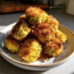 A pile of golden brown, crispy Air Fryer Crispy Garlic Dill Pickles bites stacked high on a light-colored bowl.
