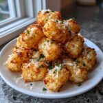A mound of golden brown Air Fryer Crispy Garlic Parmesan Tater Tots sprinkled with grated cheese and parsley.