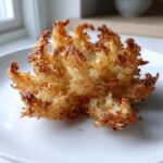 A single, perfectly cooked Air Fryer Crispy Mini Blooming Onions Golden Fun resting on a white plate.