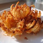 A single, perfectly cooked Air Fryer Crispy Mini Blooming Onions Golden Fun sitting on a white plate.