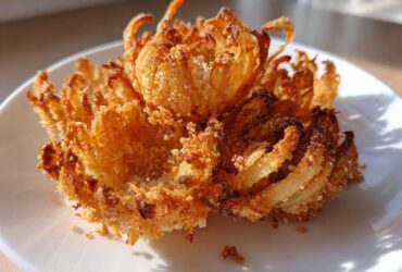 A single, perfectly cooked Air Fryer Crispy Mini Blooming Onions Golden Fun sitting on a white plate.