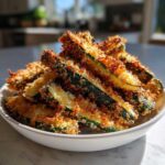 A white bowl piled high with Air Fryer Crispy Parmesan Crusted Zucchini Spears, perfectly golden brown.