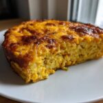 A close-up of a baked slice of Cheesy Lentil Bake Comfort Food with a golden, bubbly cheese crust.
