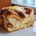 A close-up of a slice of Cinnamon Swirl Bread Butter showing the soft interior and melting butter on top.