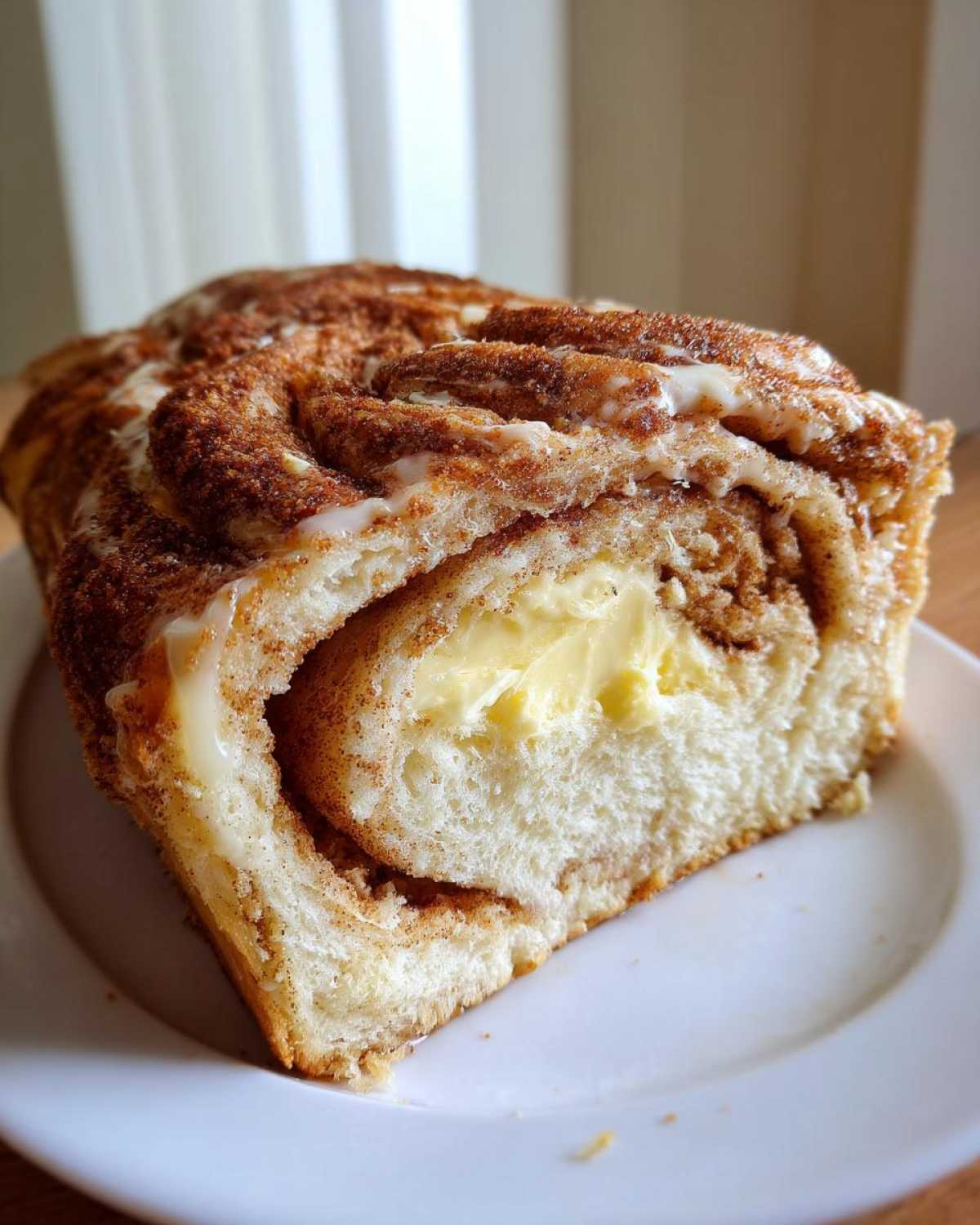 Close-up of a slice of Cinnamon Swirl Bread Butter showing the rich cinnamon swirl and a generous layer of melted butter filling.