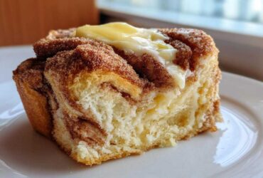 A close-up of a slice of Cinnamon Swirl Bread Butter showing the soft interior and melting butter on top.