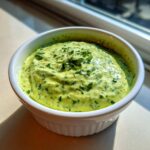 A close-up of thick, vibrant green Copycat Green Goddess Ranch Dressing topped with fresh parsley in a white ramekin.