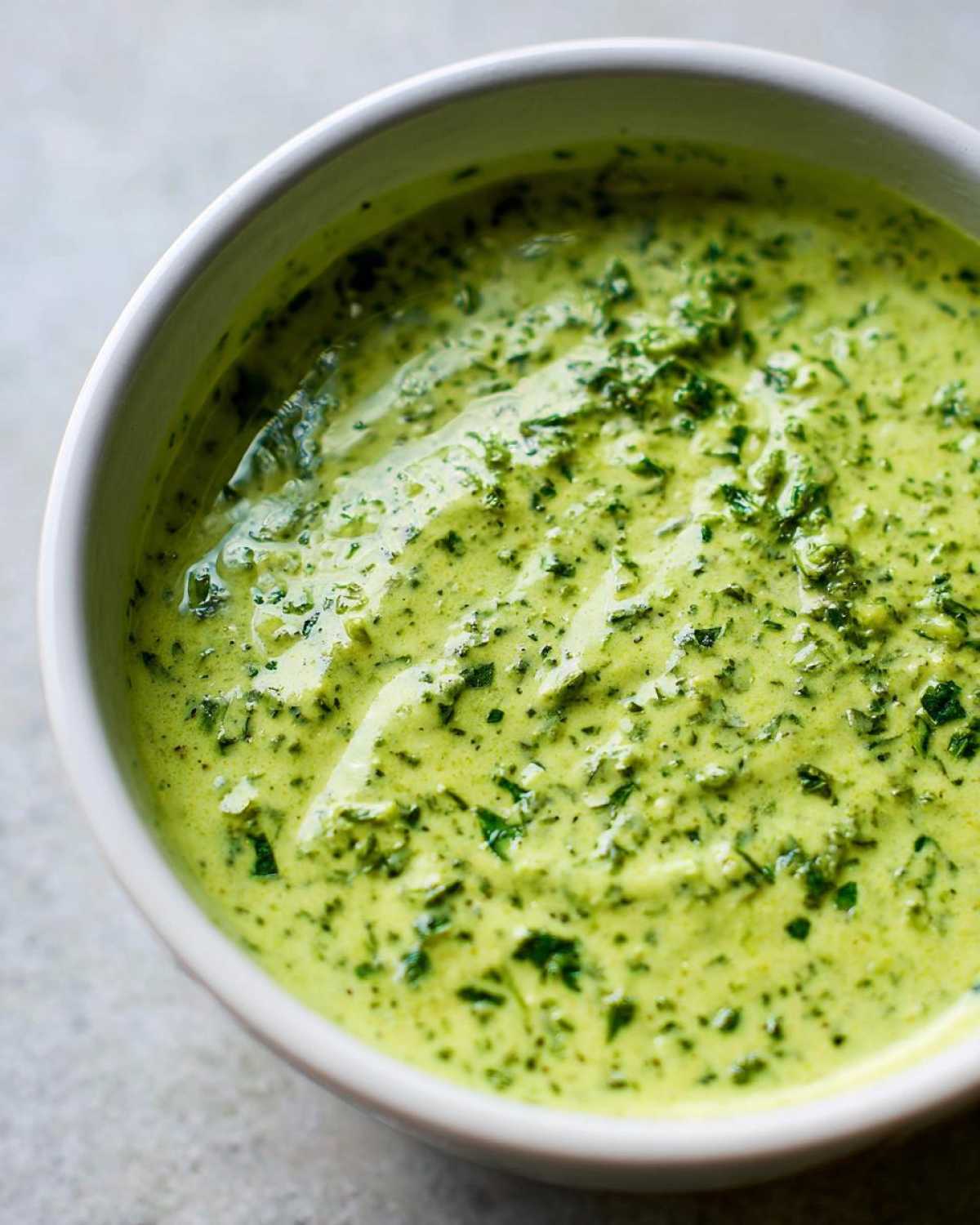 A close-up shot of thick, vibrant green Copycat Green Goddess Ranch Dressing in a white bowl.