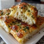 Close-up of soft, fluffy Copycat Italian Restaurant Soft Garlic Breadsticks, topped with melted butter, Parmesan, and parsley.
