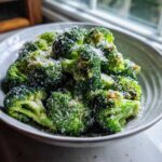 Close-up of vibrant green broccoli florets generously topped with grated parmesan cheese, ready to serve.
