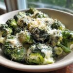 A close-up of Copycat Longhorn Garlic Parmesan Broccoli florets coated in a creamy sauce and topped with grated cheese.