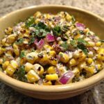 A close-up view of creamy, charred corn kernels mixed with red onion and cilantro, representing the Copycat Mexican Grill Corn Salsa.