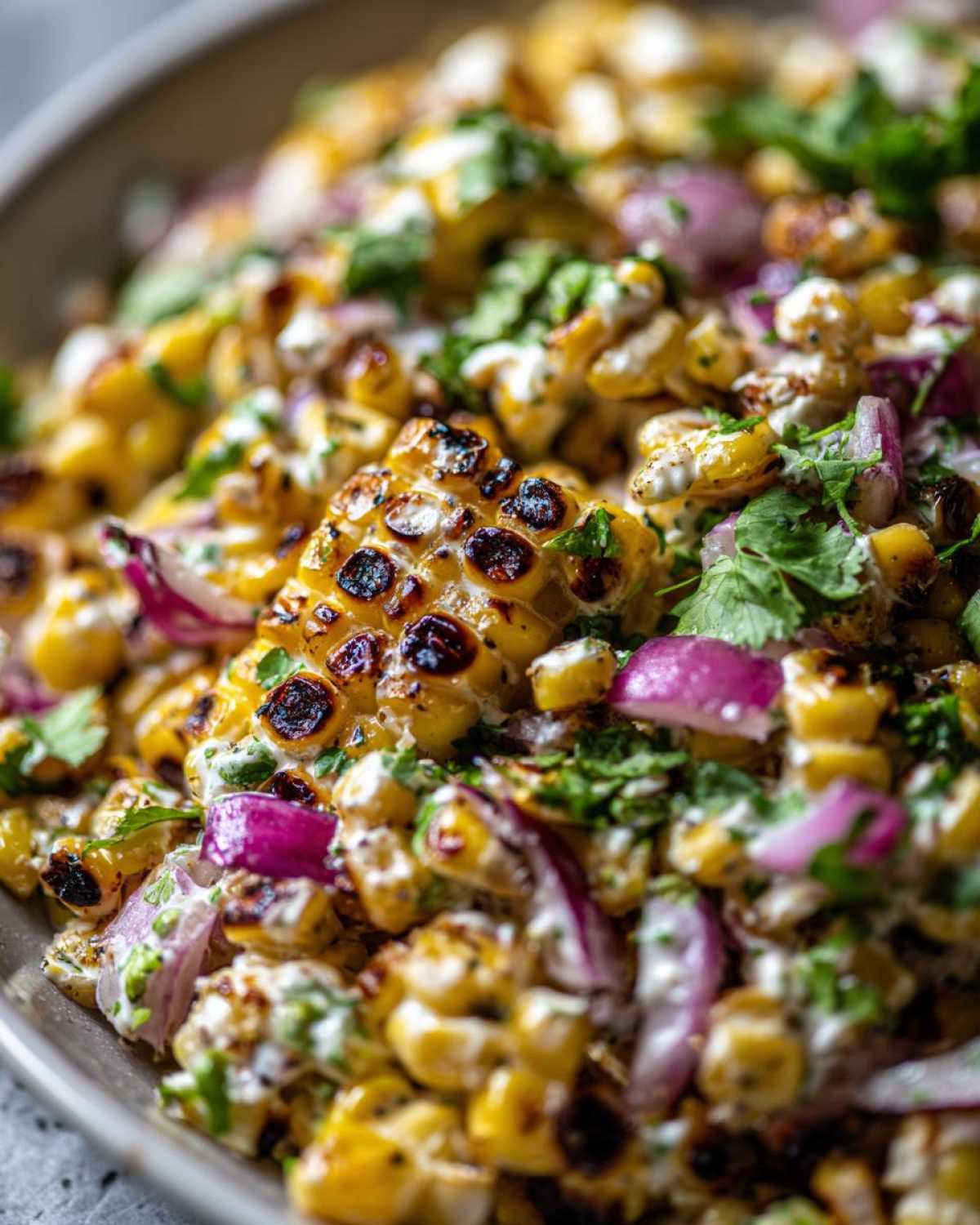 Close-up of charred corn kernels mixed with red onion, cilantro, and a creamy dressing in this Copycat Mexican Grill Corn Salsa.