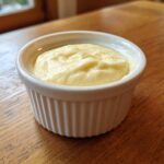 A small white ramekin filled with creamy Copycat Pizza Garlic Parmesan Dip Sauce on a wooden table.