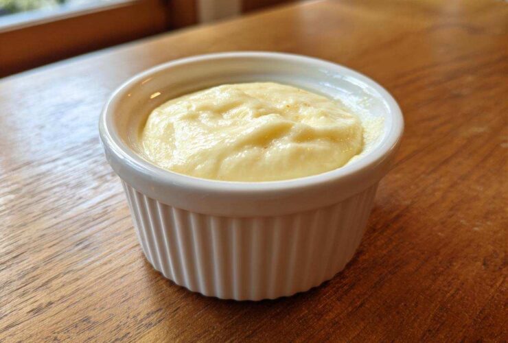 A small white ramekin filled with creamy Copycat Pizza Garlic Parmesan Dip Sauce on a wooden table.