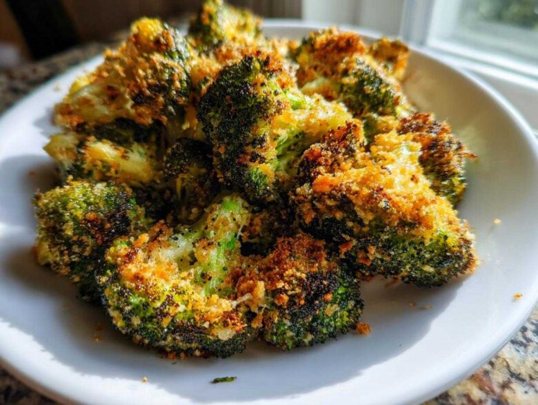 Close-up of crispy air fryer broccoli parmesan florets piled high on a white plate.