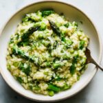 Close-up of a bowl filled with Easy Creamy Asparagus Risotto, topped with Parmesan and fresh dill.