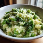Close-up of Easy Creamy Asparagus Risotto topped with grated Parmesan cheese in a white bowl.