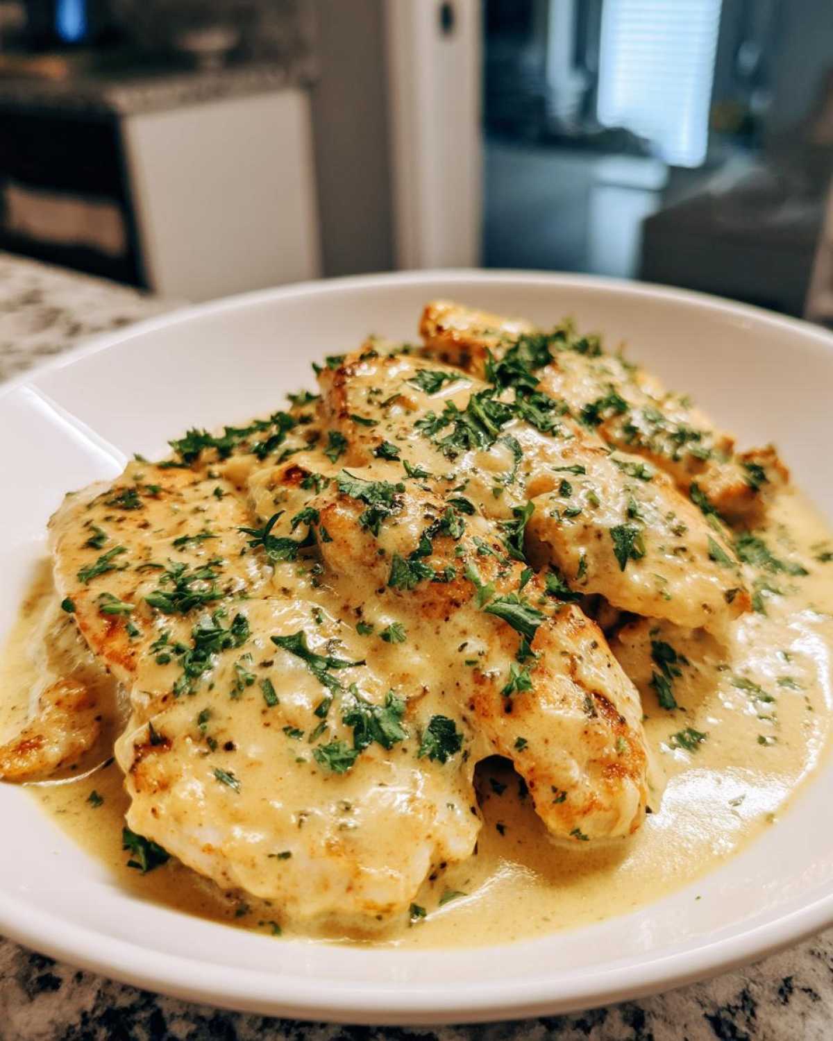 Close-up of seared chicken cutlets smothered in a creamy garlic lemon sauce and topped with fresh parsley.