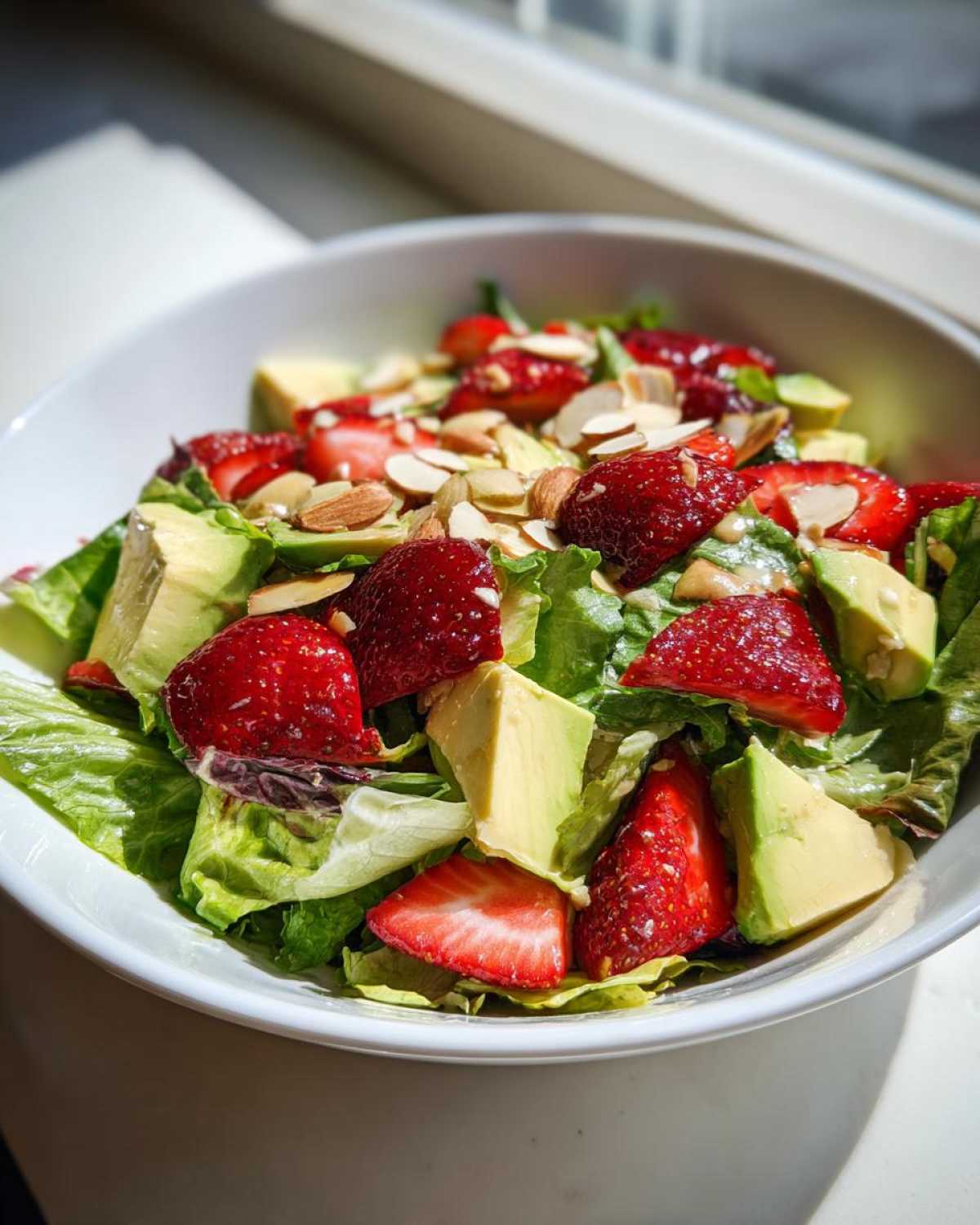 Close-up of a vibrant Easy Strawberry Avocado Salad with sliced strawberries, avocado chunks, and slivered almonds.