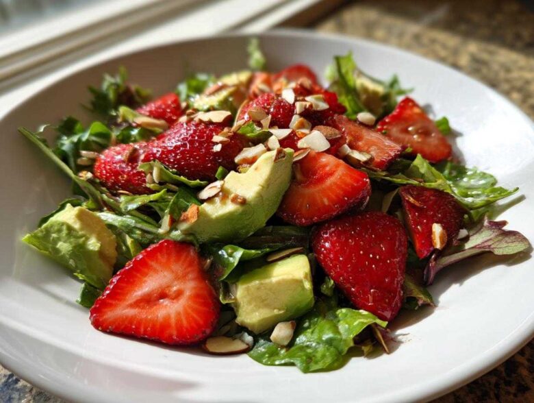 A vibrant bowl of Easy Strawberry Avocado Salad featuring sliced strawberries, avocado chunks, mixed greens, and slivered almonds.