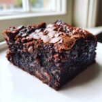 A single, rich, fudgy Nutella Brownies Chocolate square with a crackly top, sitting on a white plate.